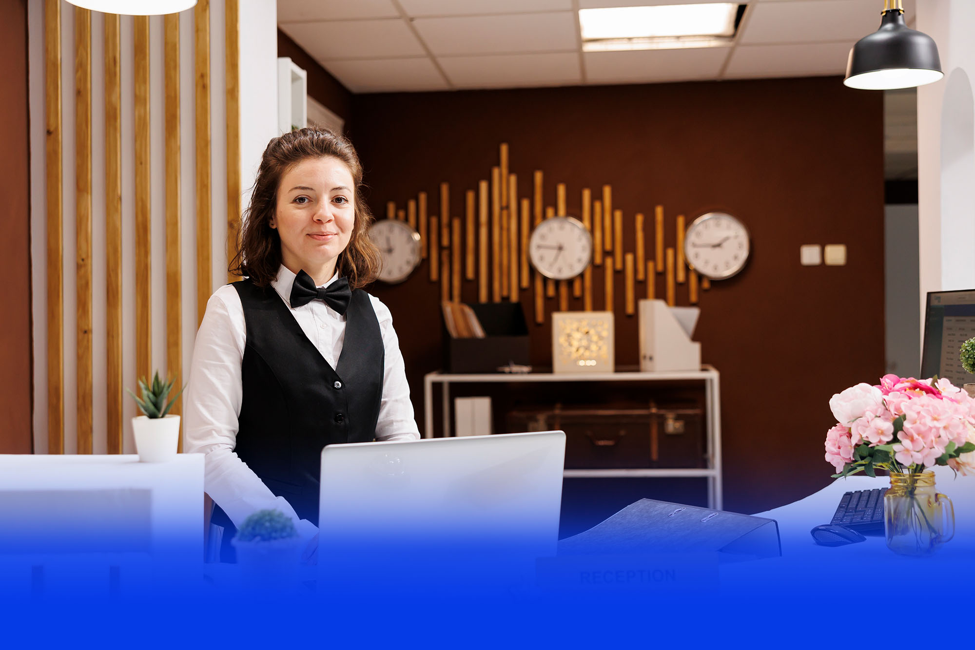 Hotelmitarbeiterin an der Rezeption mit Weltzeituhren im Hintergrund