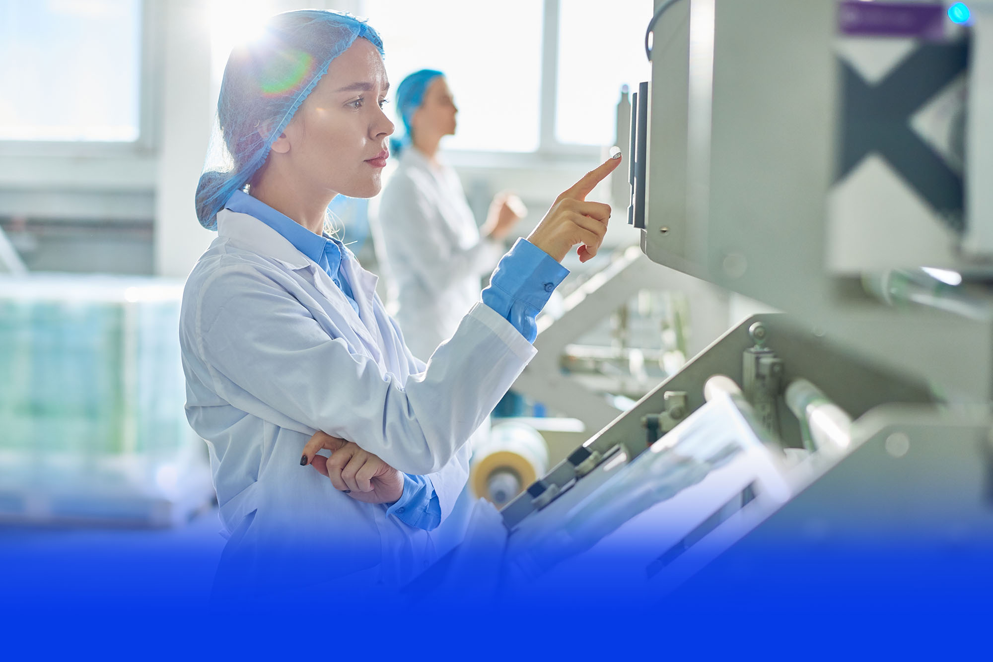 Mitarbeiterin im Reinraum-Kittel bedient eine Produktionsmaschine
