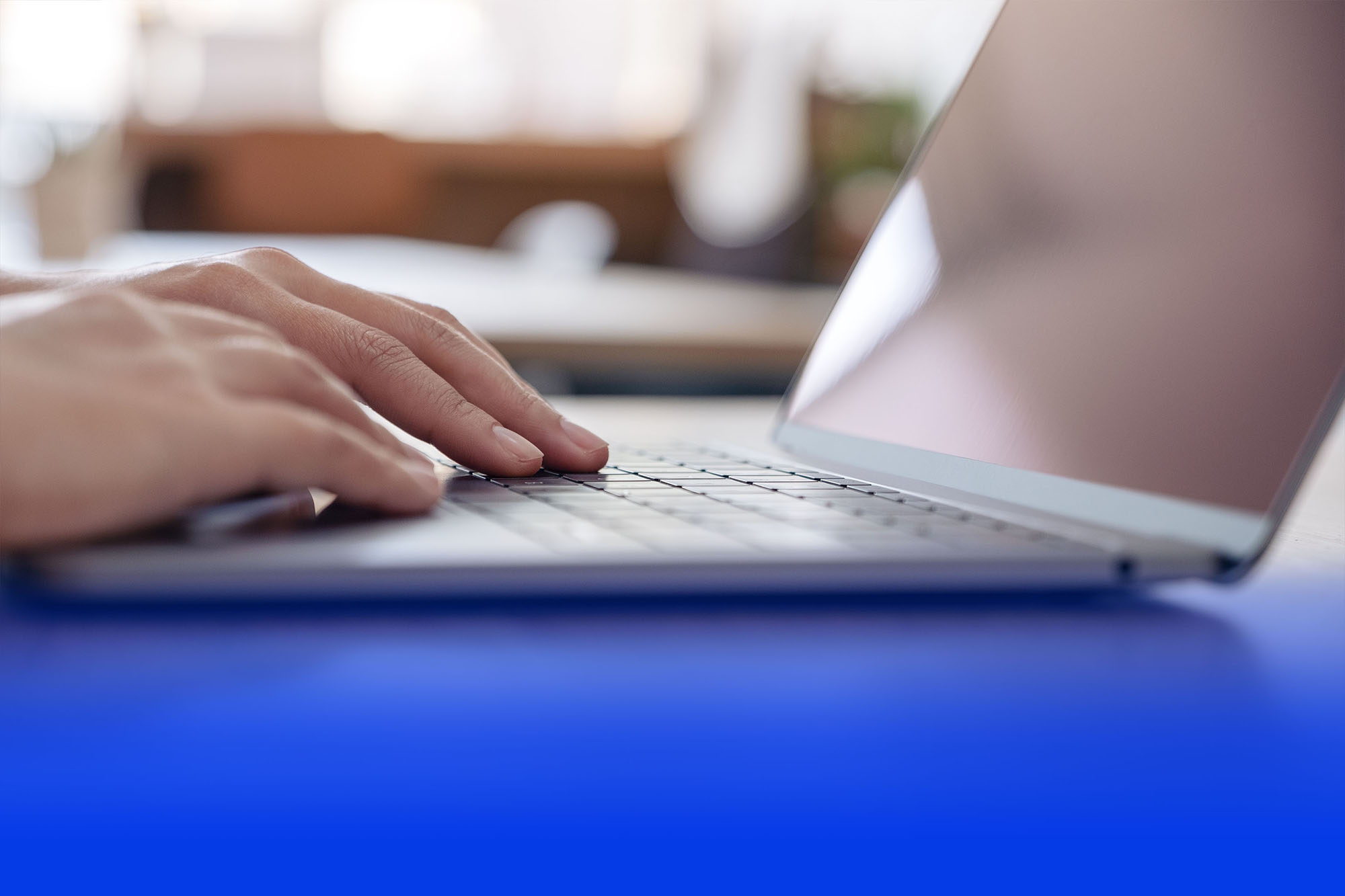 Hand tippt auf einer Laptop-Tastatur in moderner Büroumgebung