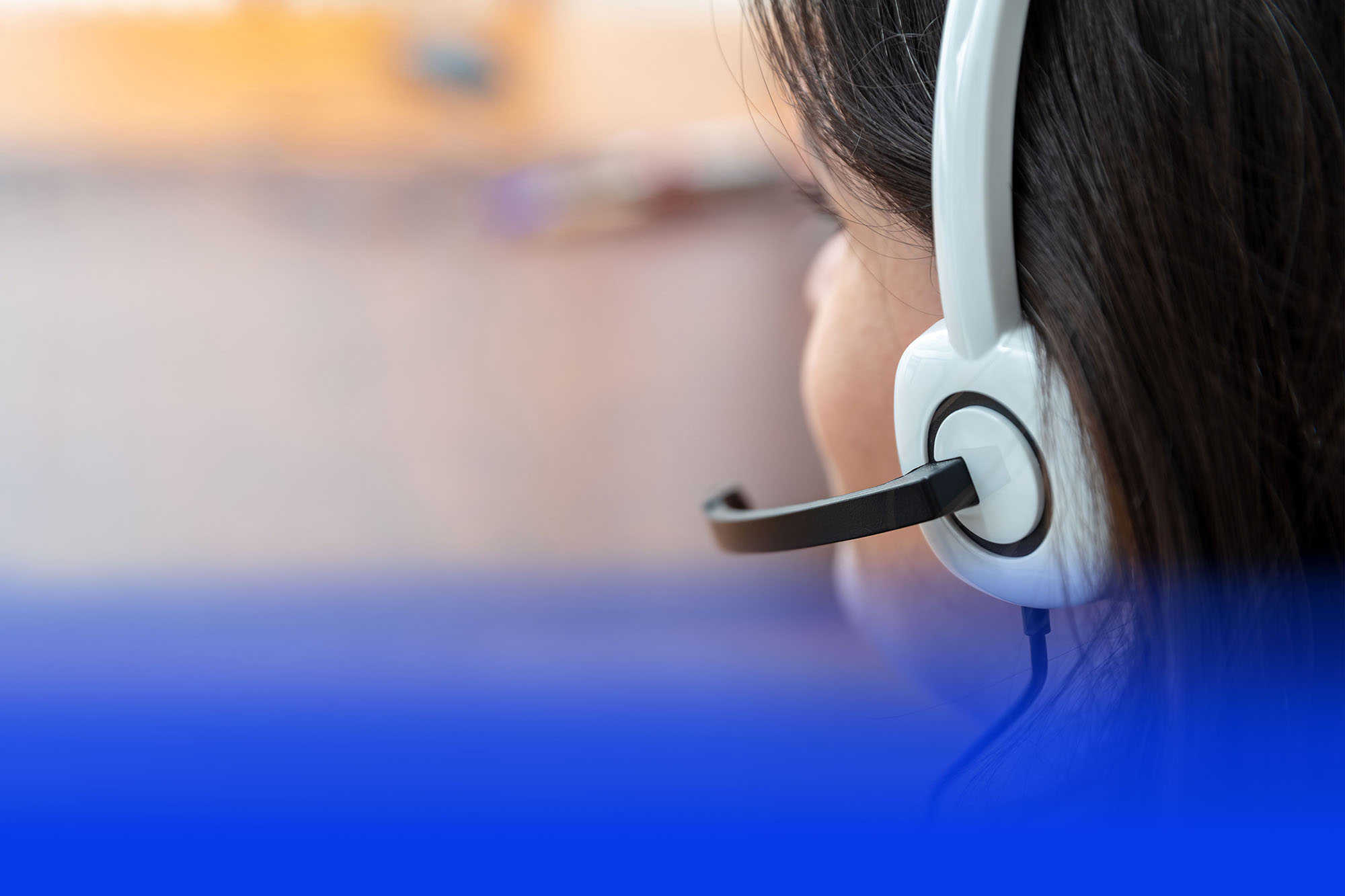 Service-Mitarbeiterin mit Headset von hinten am Beratungsplatz